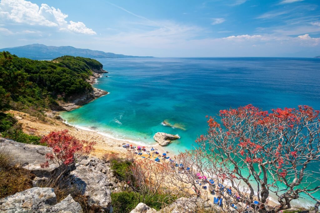 Alt Text: Aerial view of Pulebardha Beach in Albania with turquoise water and stone beach